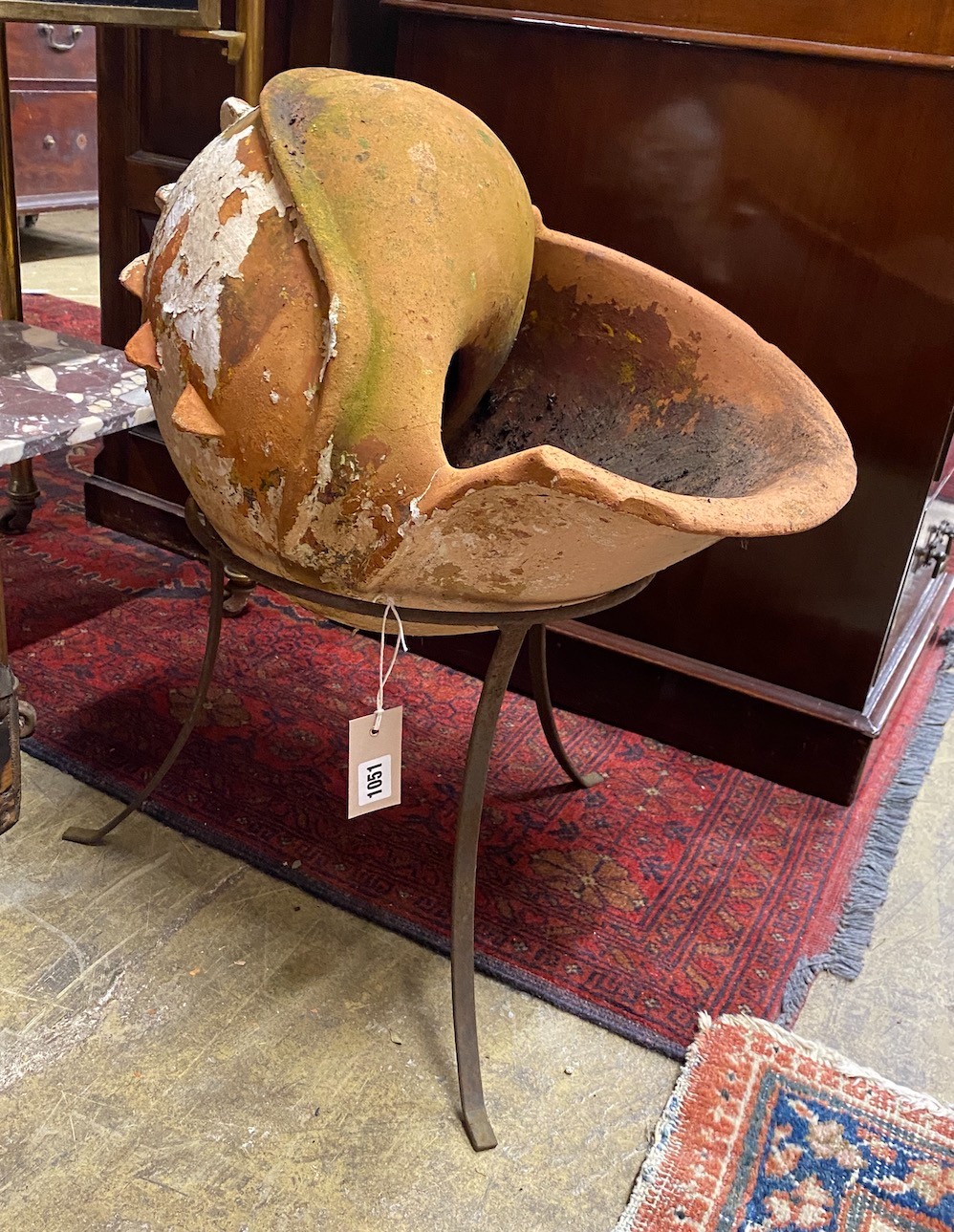 An unusual terracotta garden planter on wrought iron stand modelled as a conch shell, height 56cm